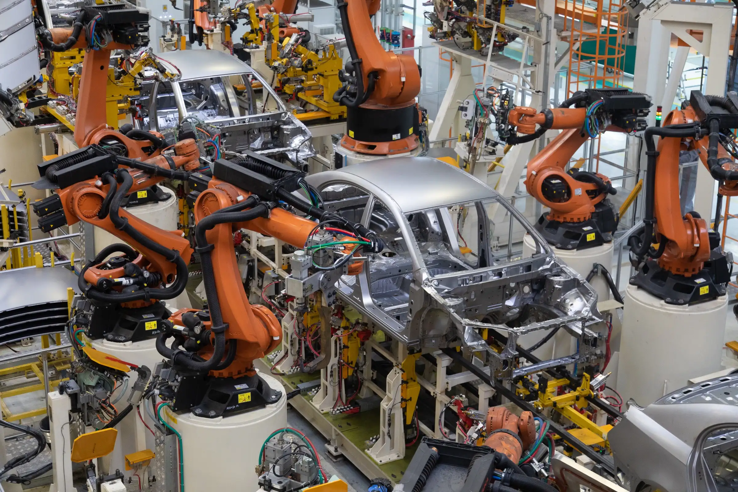 Robots industriales soldando carrocerías en una línea de ensamble automotriz